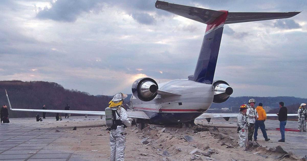 Emergency responders and firefighters at the scene of a business jet runway overrun, with the aircraft resting beyond the runway end on damaged pavement.