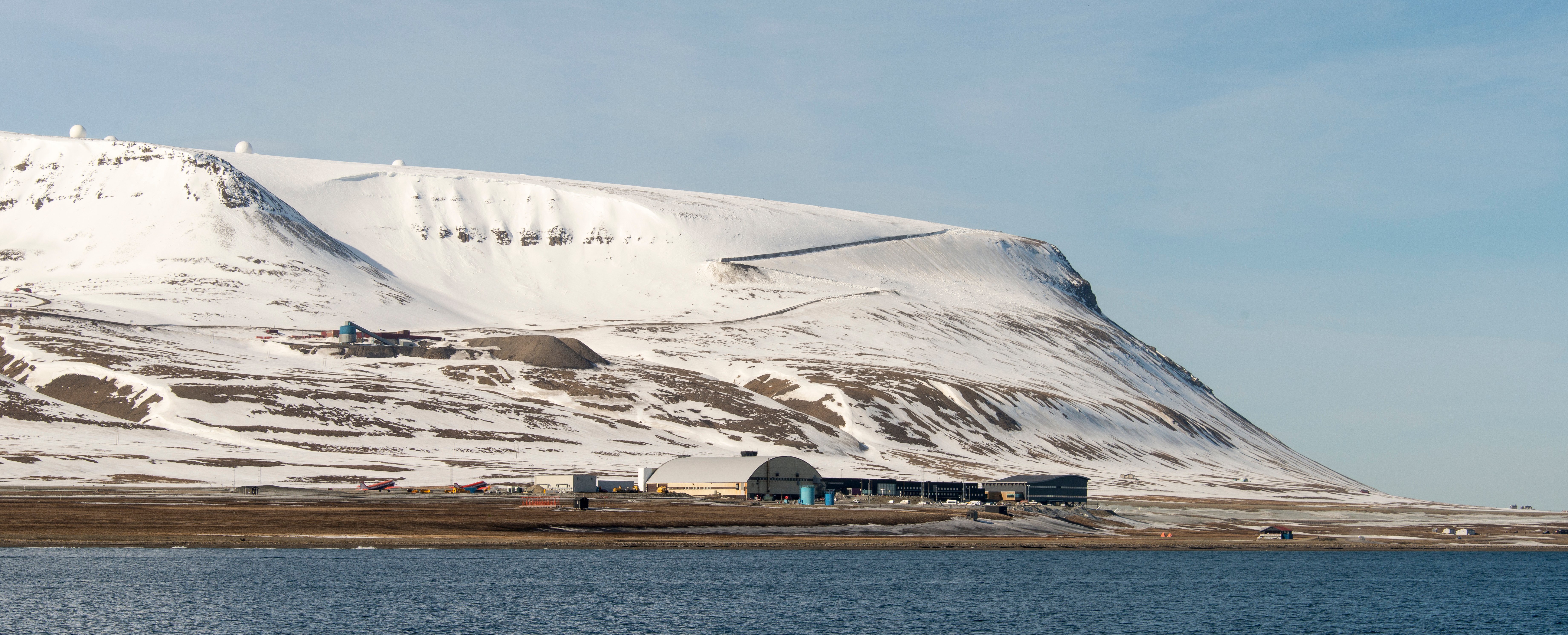 Svalbard Airport in Norway with snowy mountains and Arctic terrain in the background.